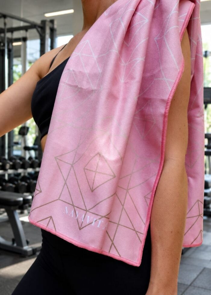 žena ve fitness centru má přes rameno hozený NAYAVITA fitness ručník Pink Lines